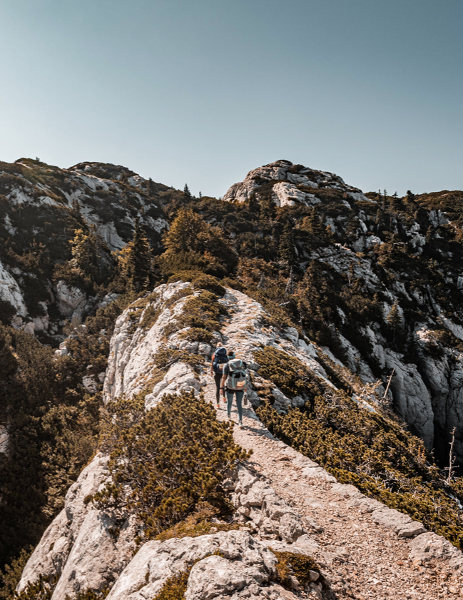 Hikers walking along a mountain ridge in Greece, embracing wellness tourism through adventure and nature.