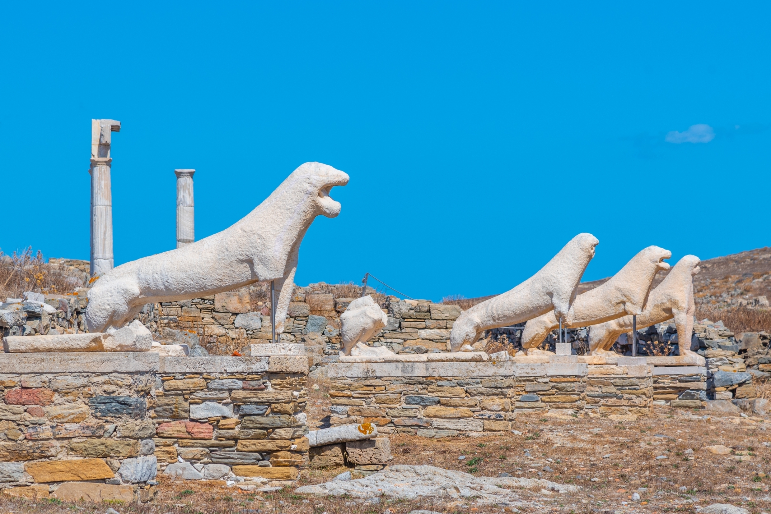 Ancient marble lion statues on Delos island, Greece, under clear blue skies, symbolizing sacred history and mythology.
