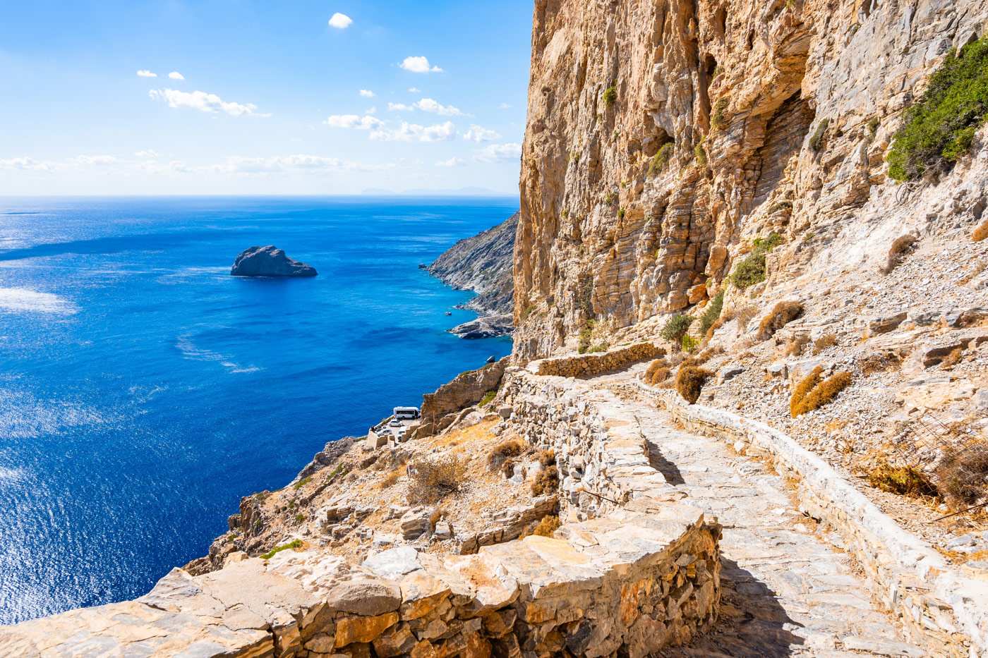 Rocky cliffside path overlooking the deep blue Aegean Sea in Amorgos island, Greece, offering serene coastal views.