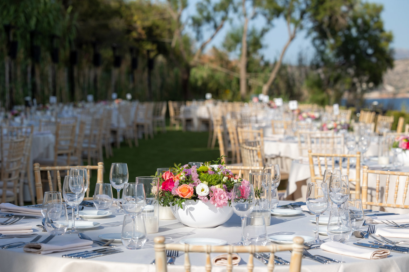 Elegant outdoor dinner setup for a corporate event in Greece, with floral centerpieces, fine tableware, and a seaside backdrop — part of a luxury team building and incentive program.