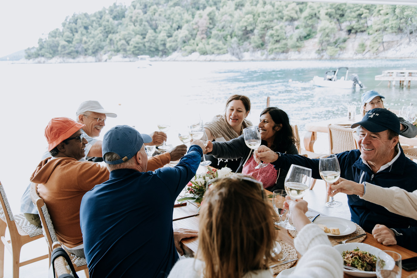 Corporate incentive trip in Greece — DMC agency organizing seaside lunch and team building experience for employees enjoying a toast.