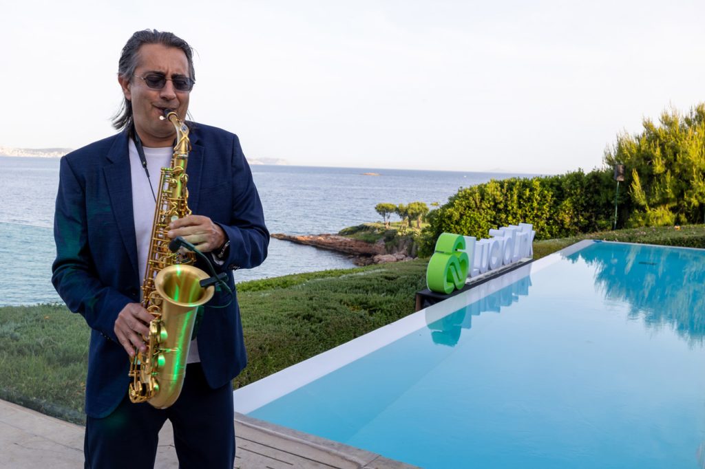 Elegant corporate event in Greece — live saxophone performance by the pool during a seaside networking reception organized by a DMC agency.
