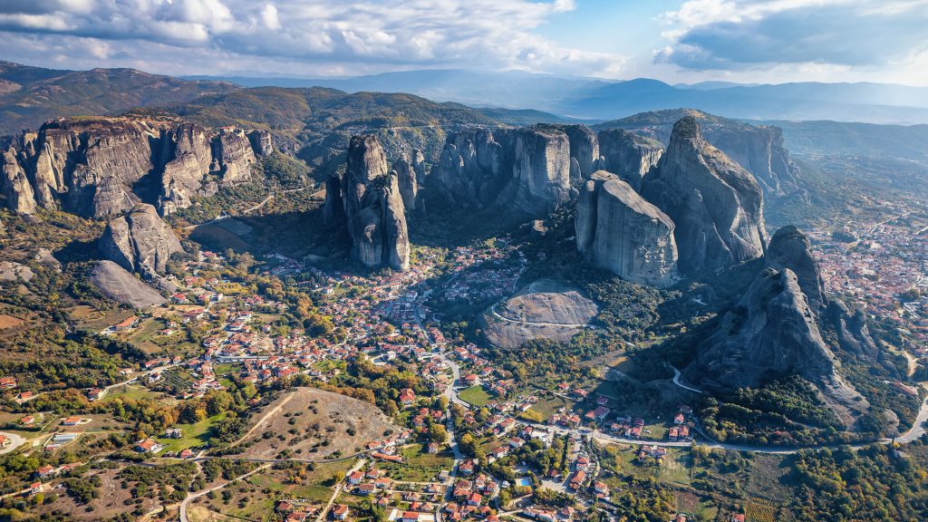 Aerial view of Meteora’s cliffs and village nestled below, under soft winter light.