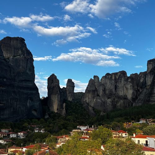 Panoramic view of Meteora’s towering rock formations rising above the village, symbolizing reflection and leadership.